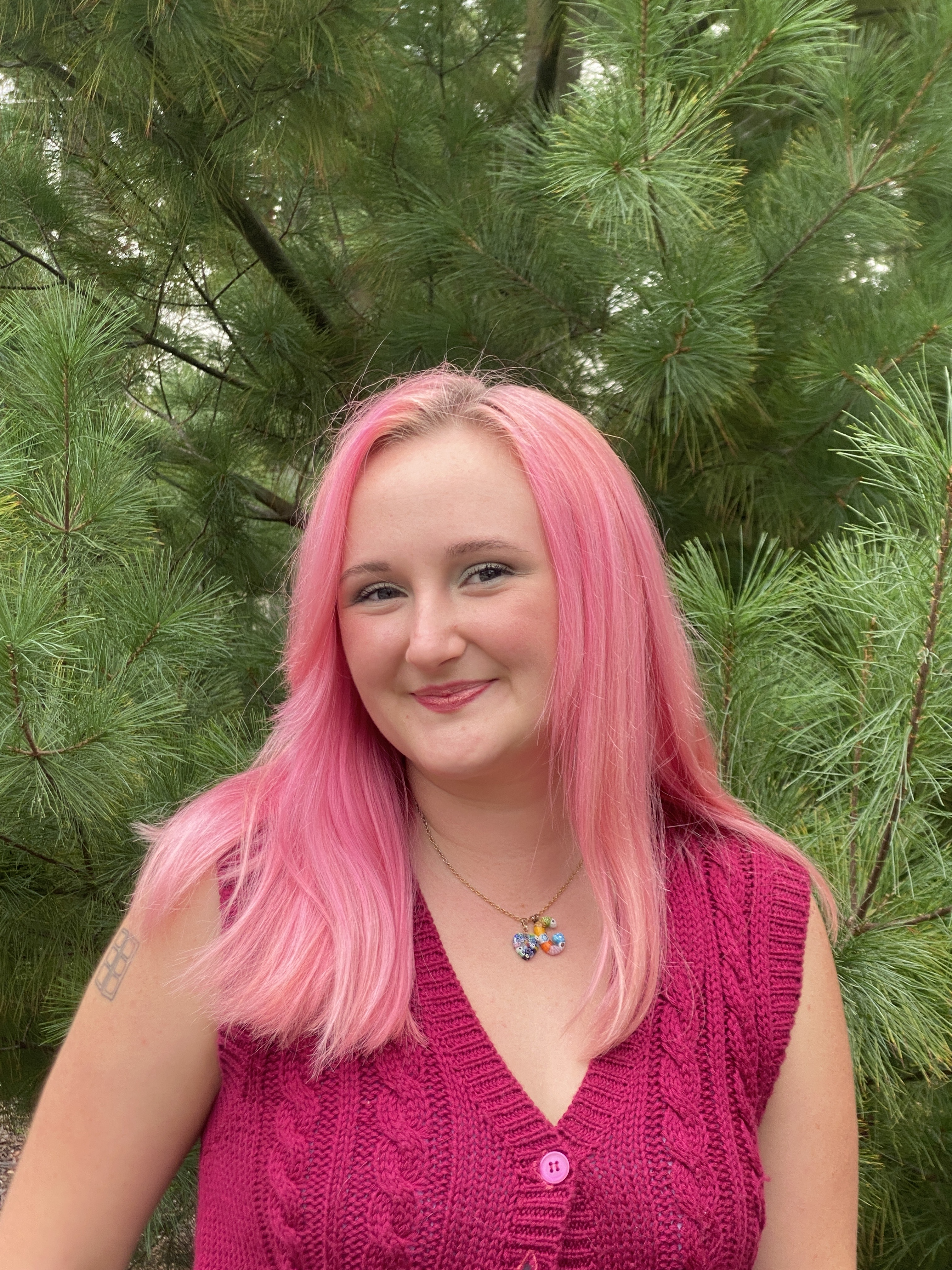 Gabbie Stokes stands in front of green foliage, smiling