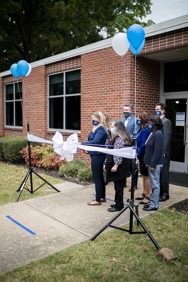 A group of UAFS administrators stand at the Writing Center front doors as Dr. Cammie Sublette and Dr. Monica Luebke cut a large white ribbon.