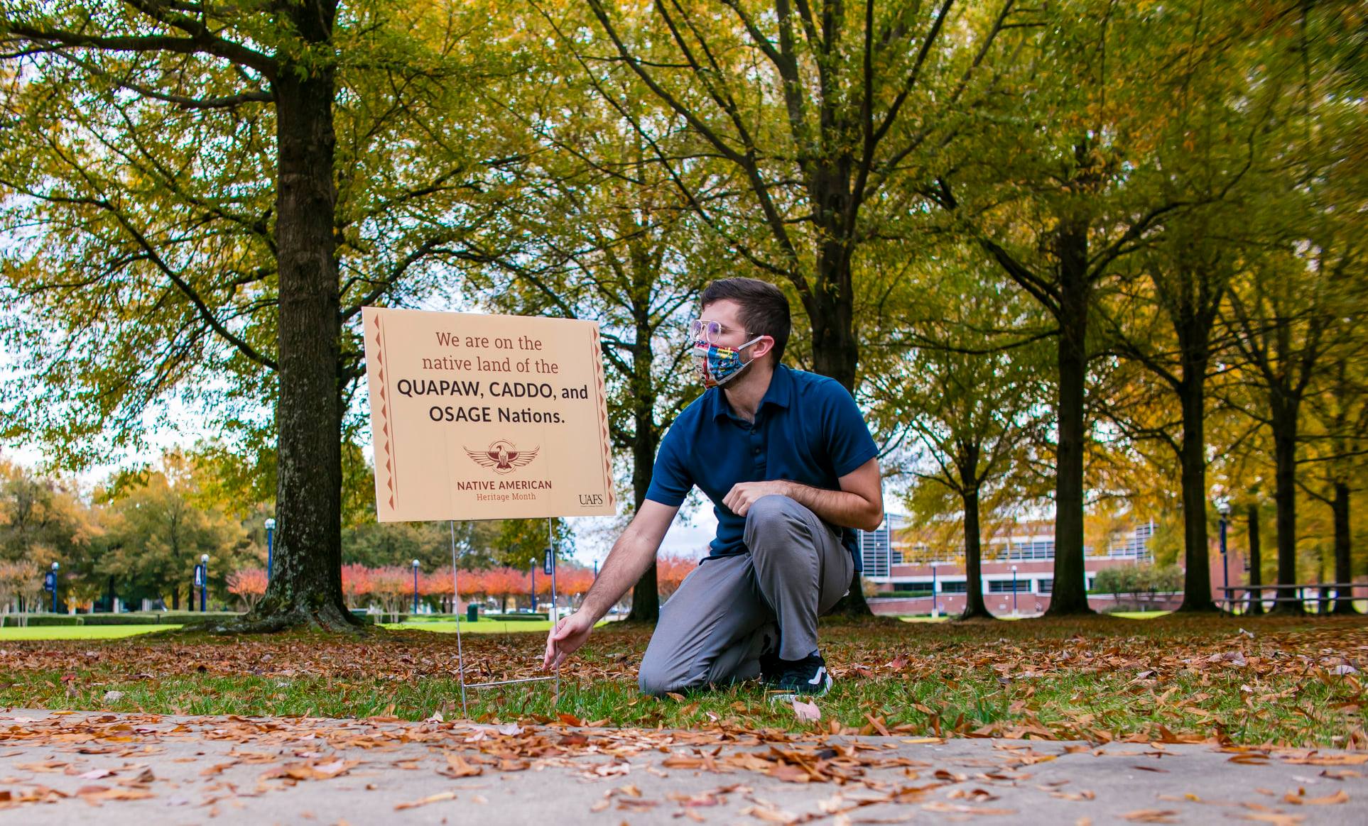 Josh Simonds planting a land acknowledgment sign that states 