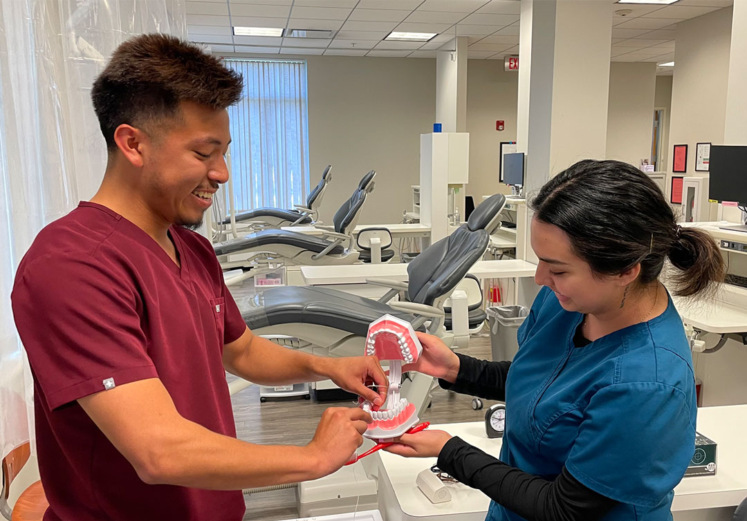 UAFS dental hygiene graduates, Jon Kevin Villeda (left) and Melissa Perez demonstrate how to floss teeth on testing equipment