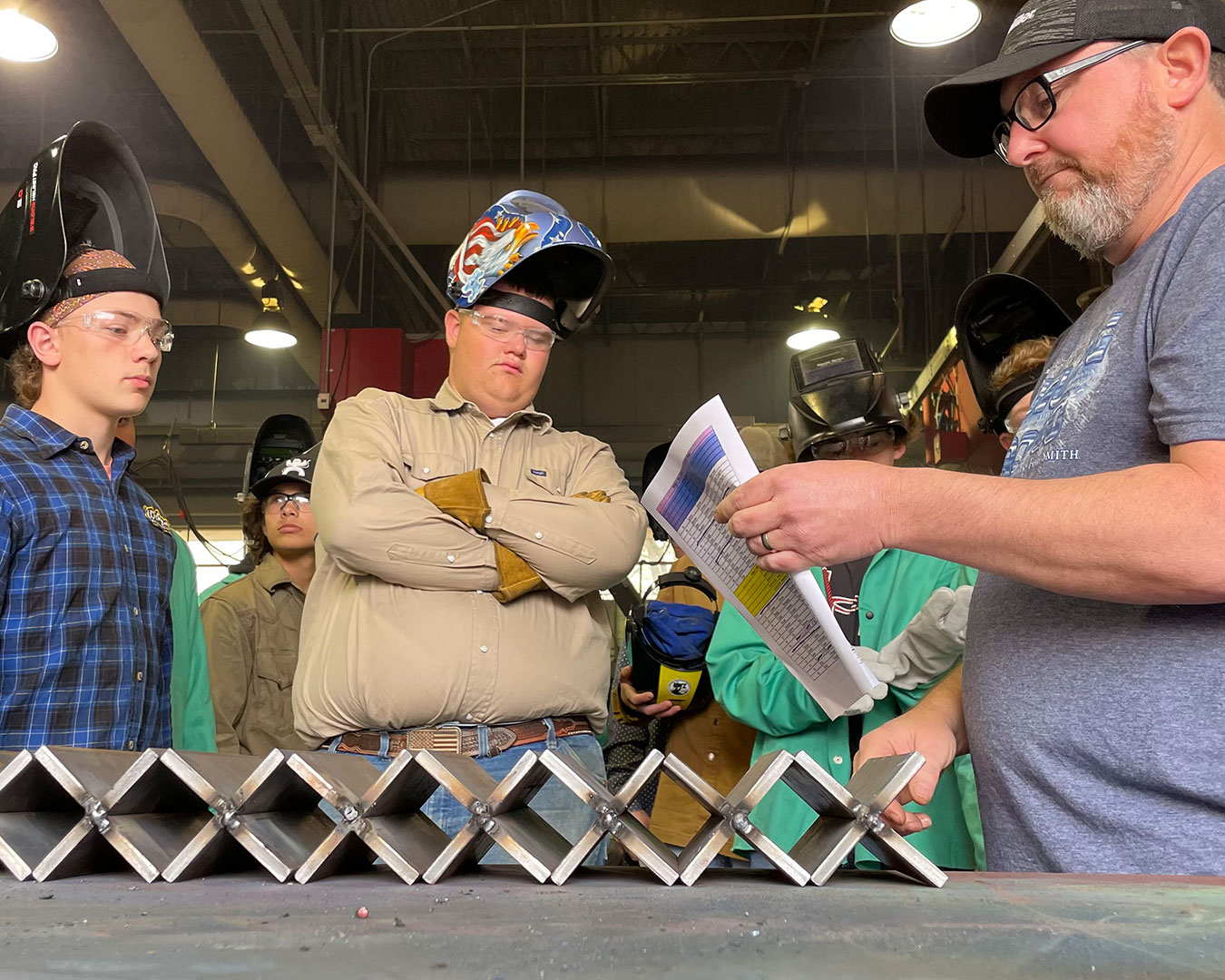 Welding instructor, Jason Keyes (right), hands out welding joints to contestants