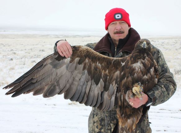 Man outside in winter, holding an eagle with one wing extended