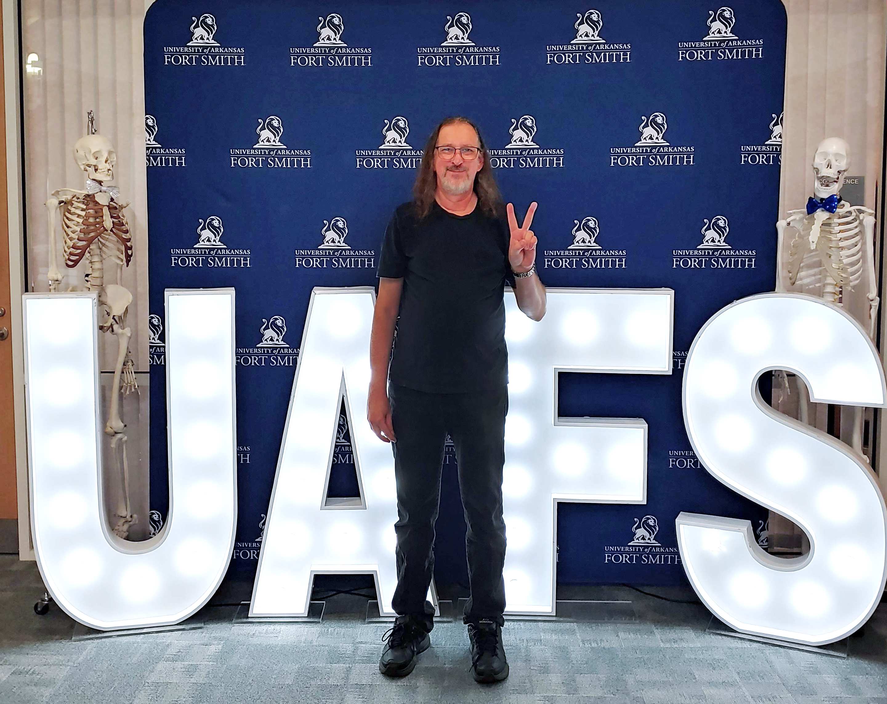 Dr. James Benjamin poses infront of a UAFS backdrop and light up letters spelling out UAFS.