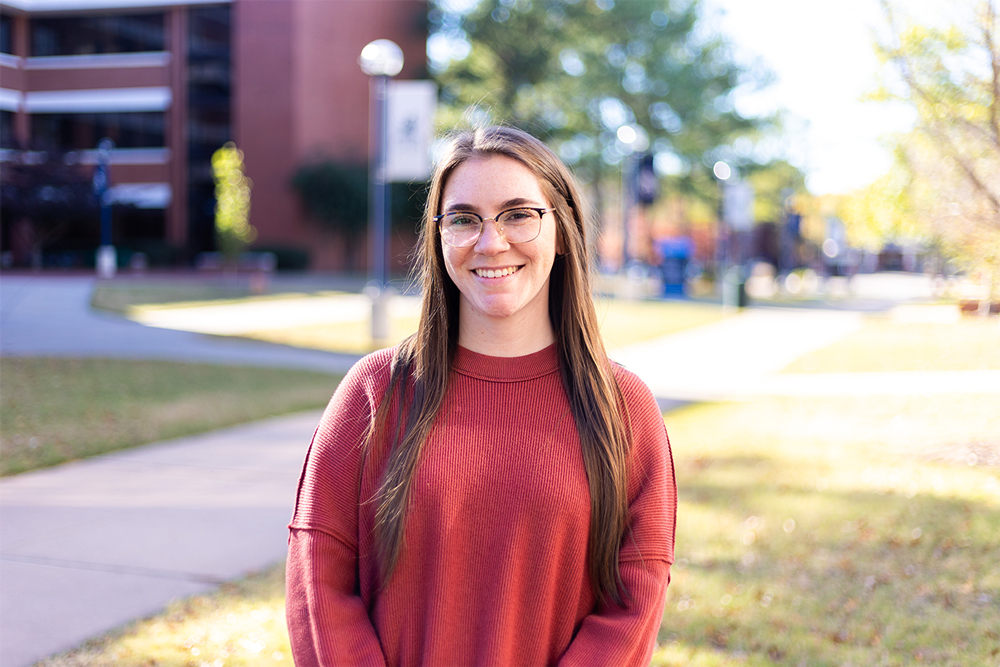 Advisor, Joellen Barthol, smiles for the camera while standing in front of the Math Science Building at UAFS.