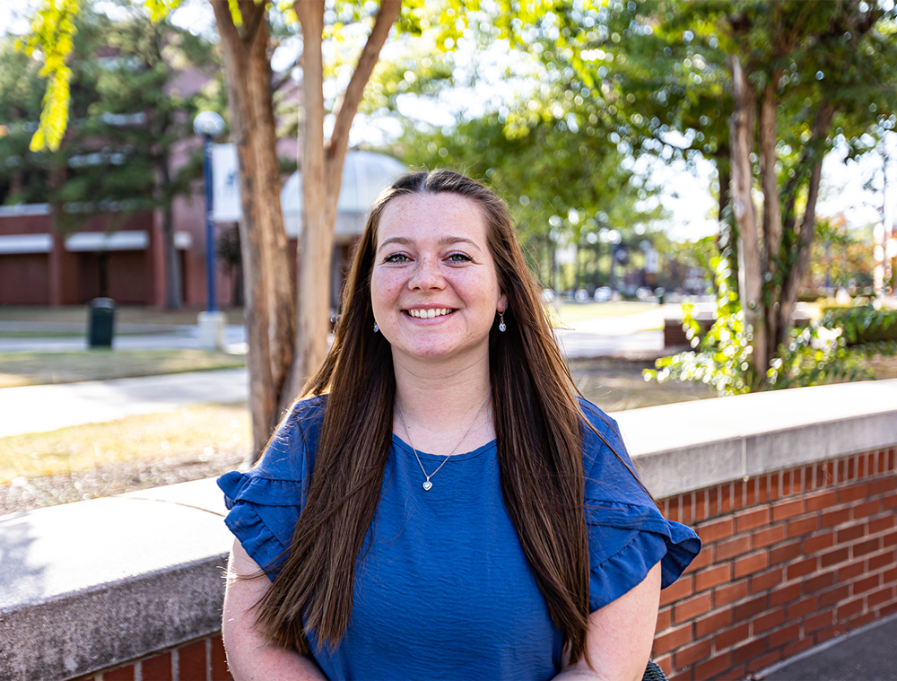 Journi Goforth smiles for the camera in front of the Smith-Pendergraft Campus Center.