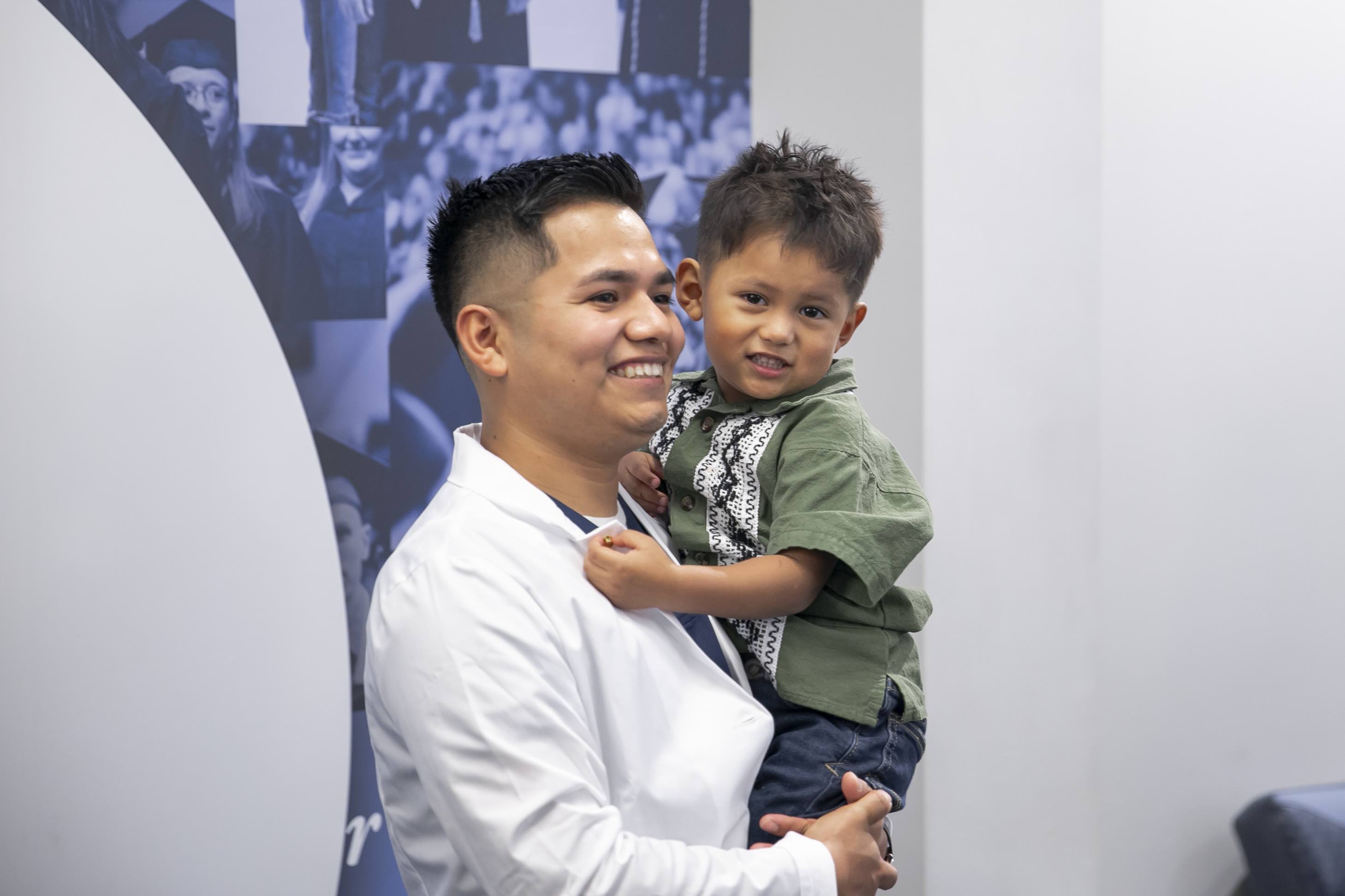 A student holds a child after the white coat ceremony