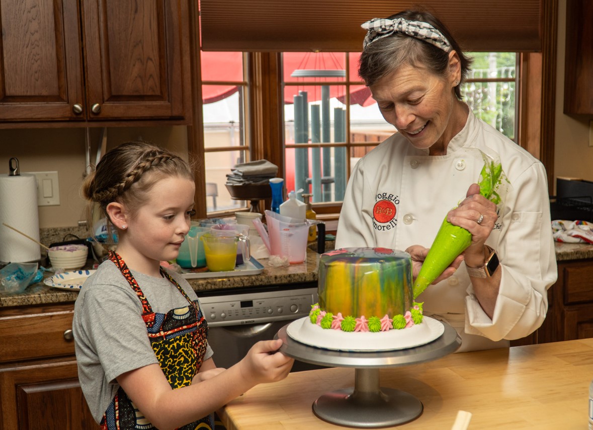 A woman decorating a cake with a child