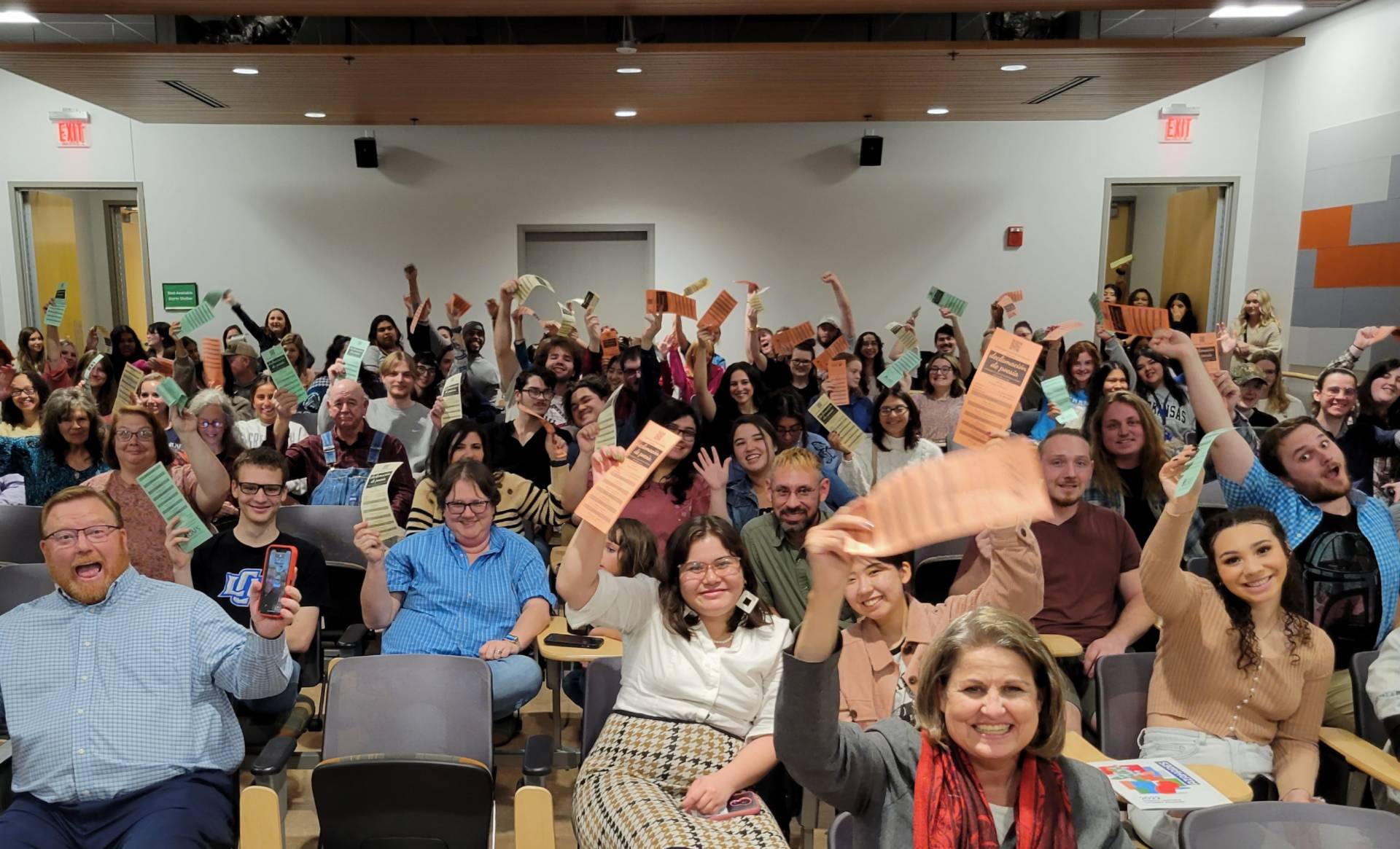 a packed theater of people holding up cards