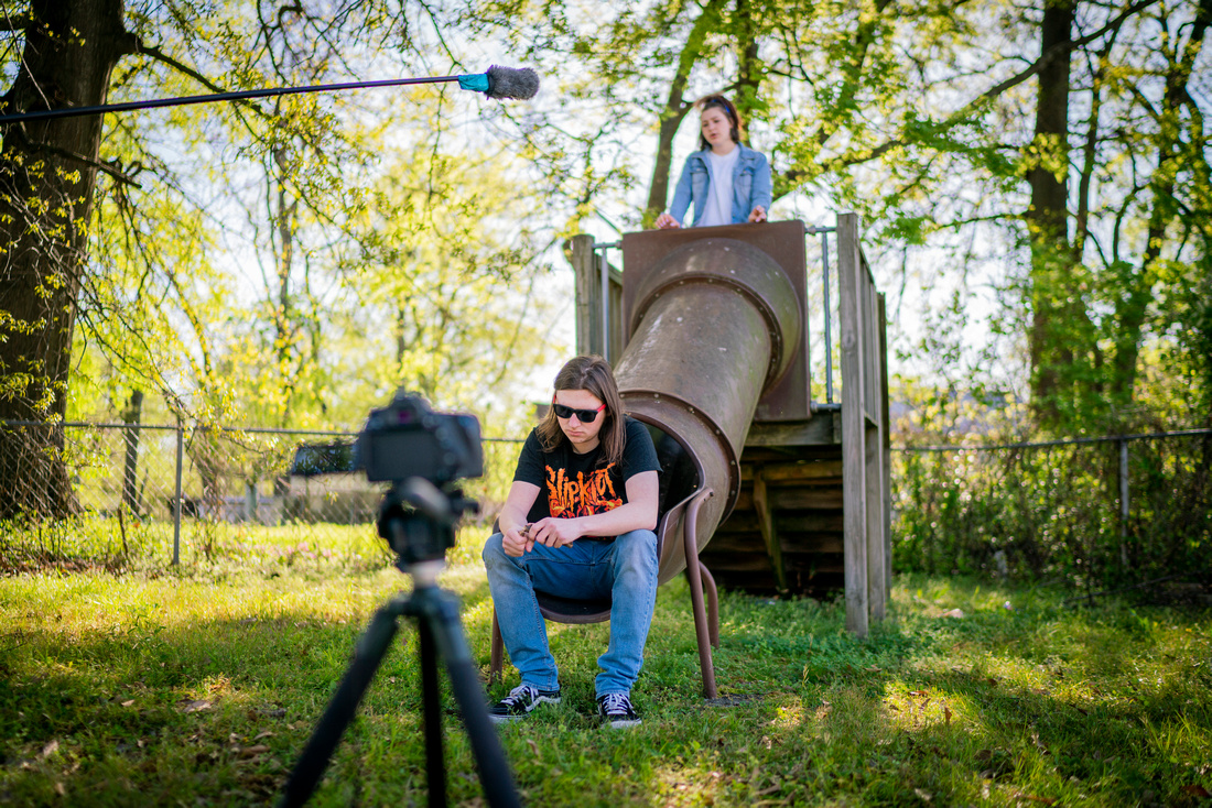 College students sit on a slide with a camera in the foreground