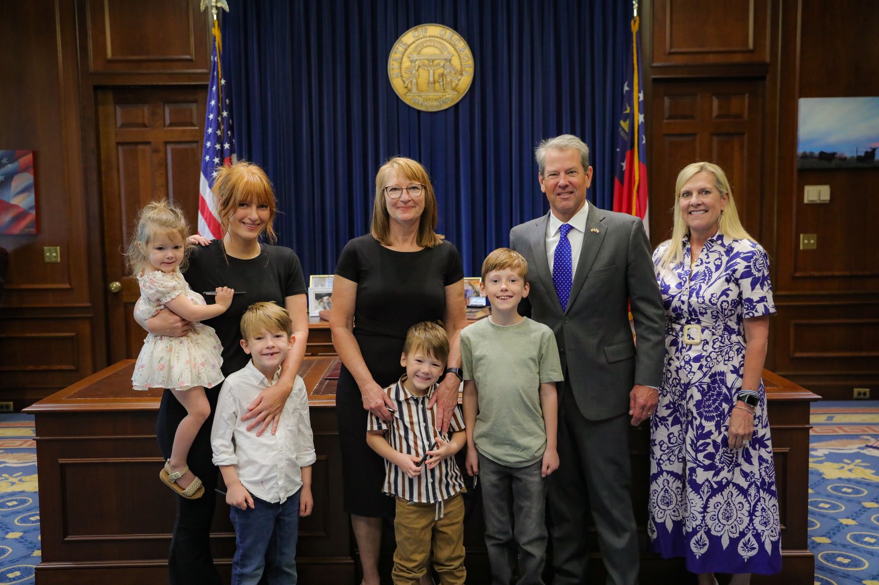 photo of four chilcdren and four adults in a formal office