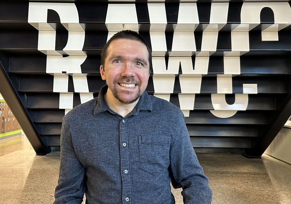 Spencer Ewing sits underneath the stairs at the RAWC with the building name painted behind him.