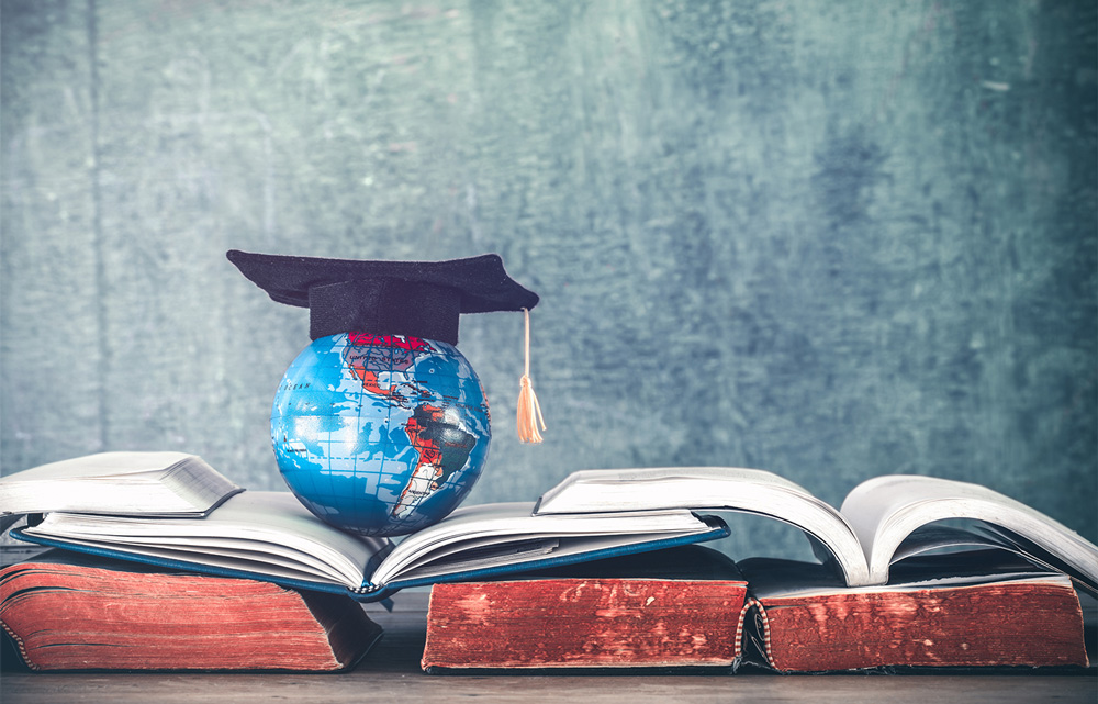 A globe with an academic cap sits atop open books