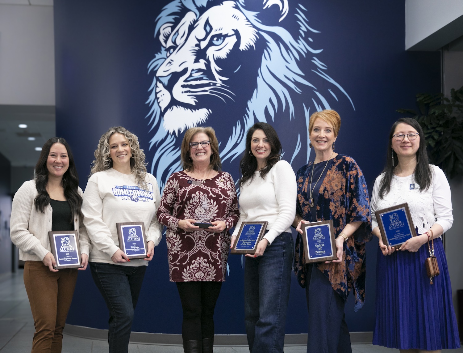 Winners of the 2025 Alumni Awards stand with their plaques. 